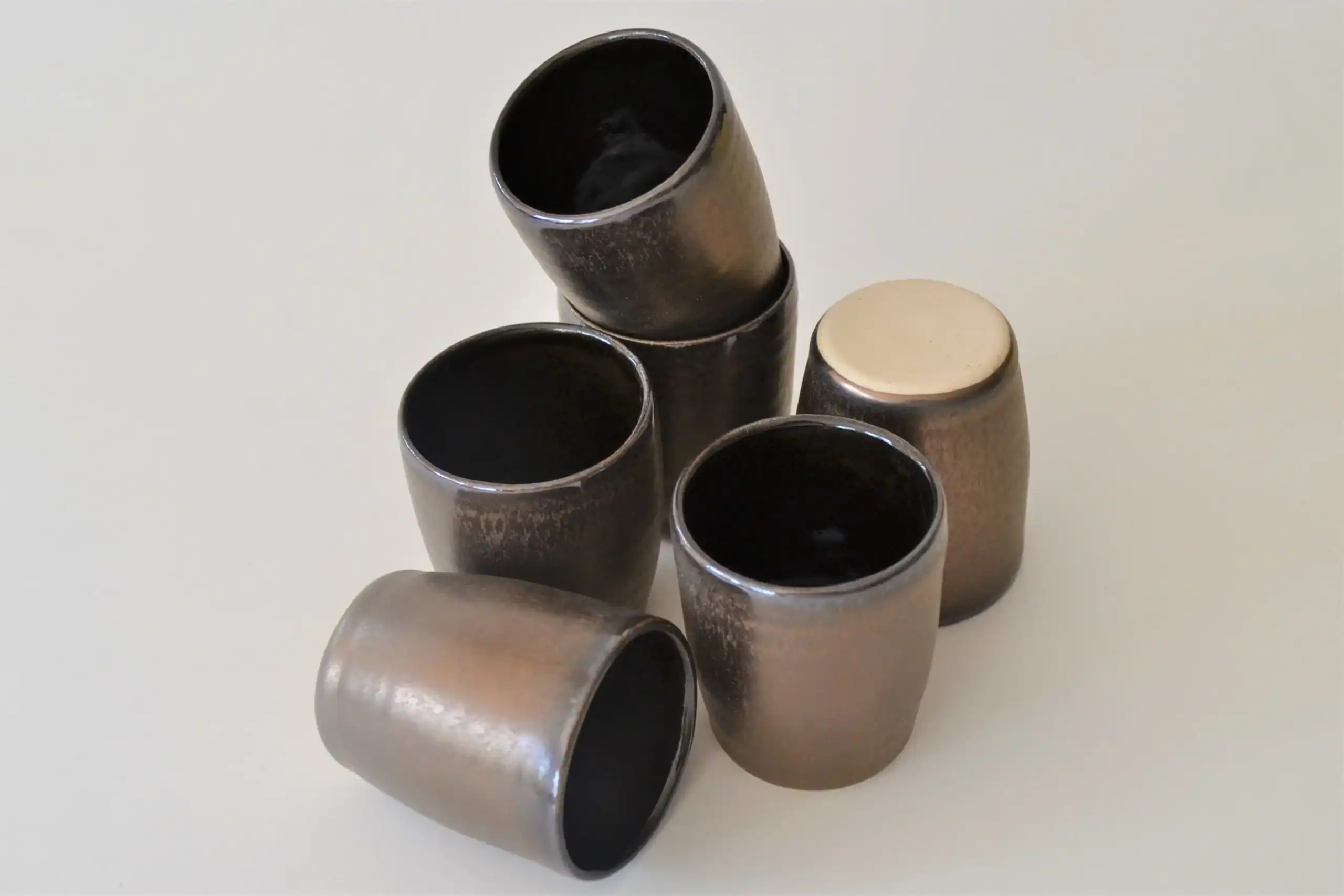 a collection of bronze pottery shot glasses
