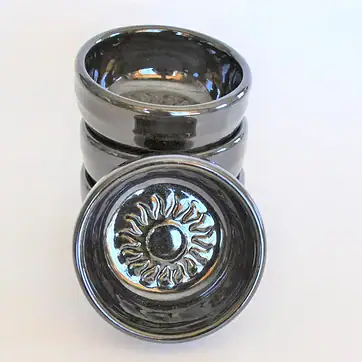 small dish with sun emblem in center, black