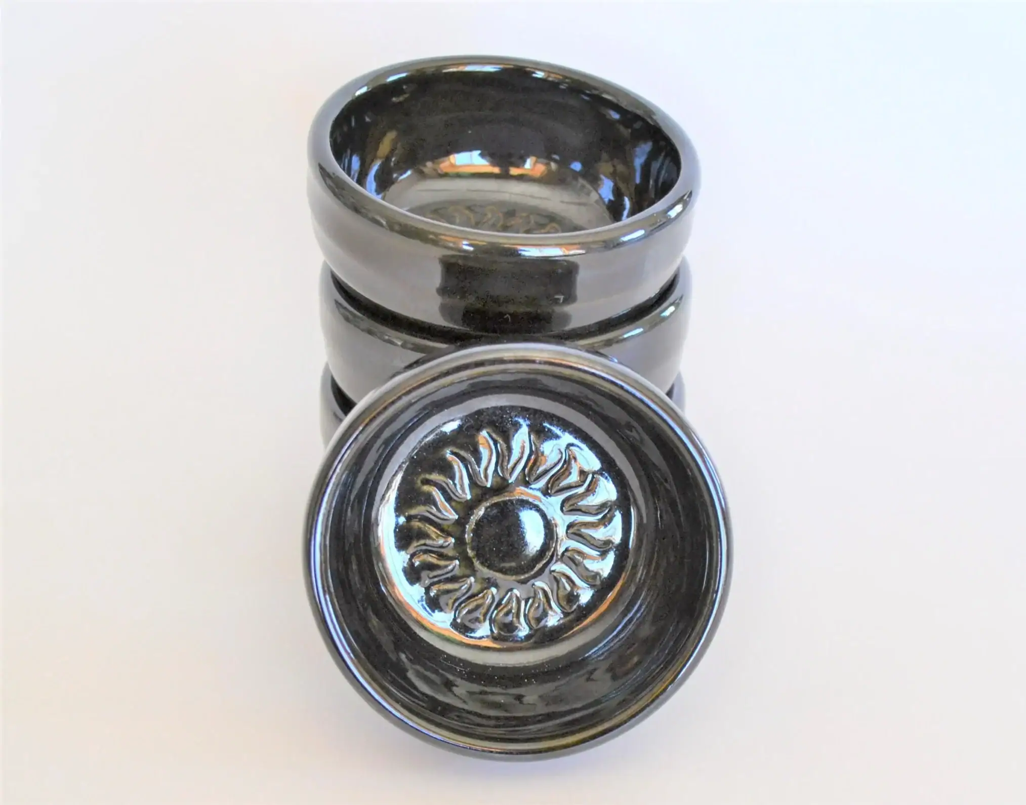 small dish with sun emblem in center, black