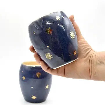 Winter Stemless Wine Glass with Gold Snowflakes, held in hand for scale