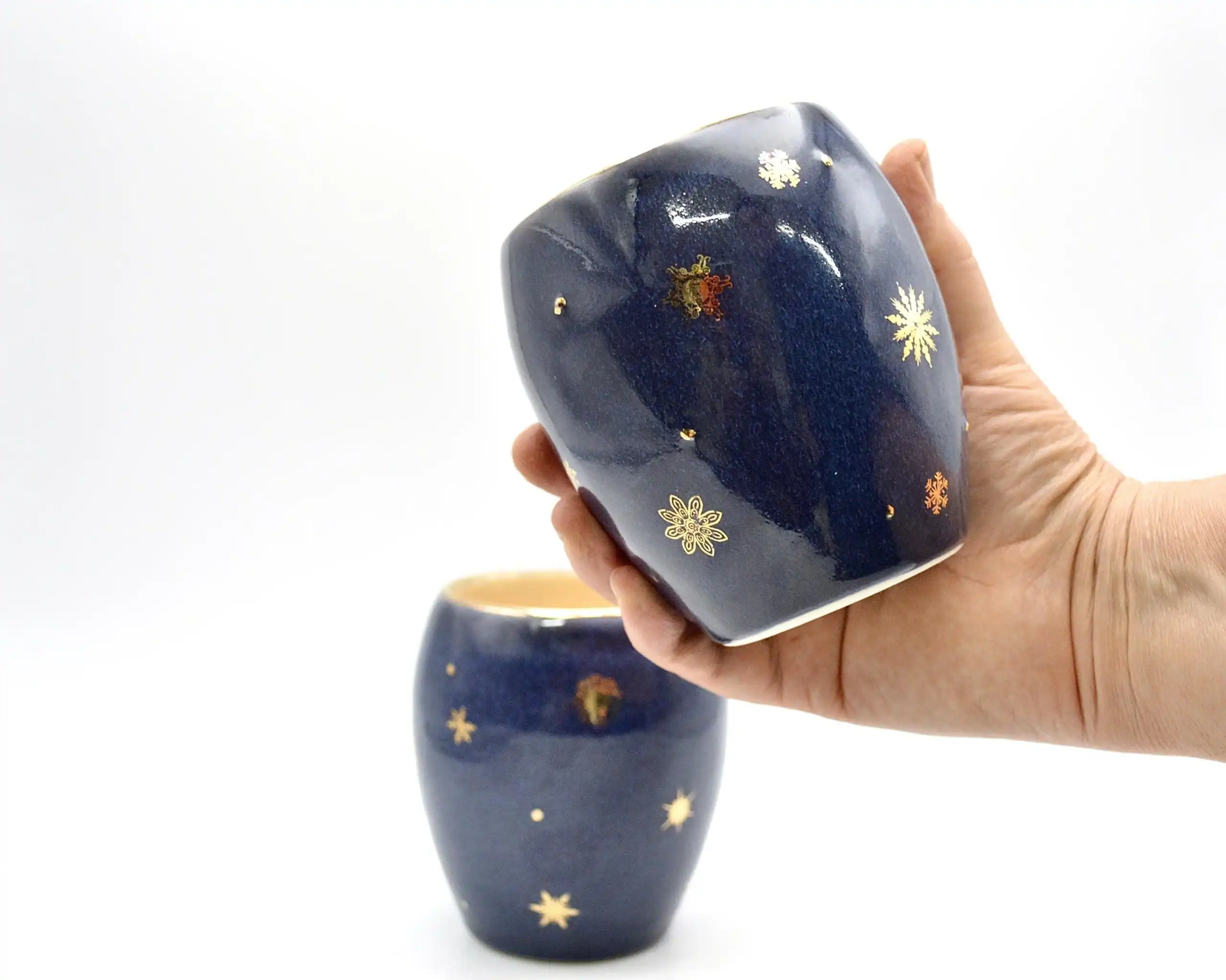 Winter Stemless Wine Glass with Gold Snowflakes, held in hand for scale